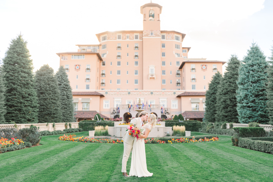 Newlyweds share a kiss in the manicured gardens behind the broadmoor hotel wedding venue