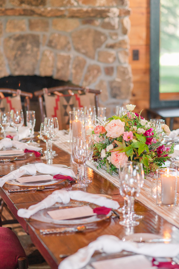 Details of a wedding reception table set up with pink flowers and white napkins and candles