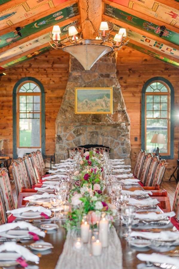 Details of a long wedding reception table in a cabin style room with stone fireplace