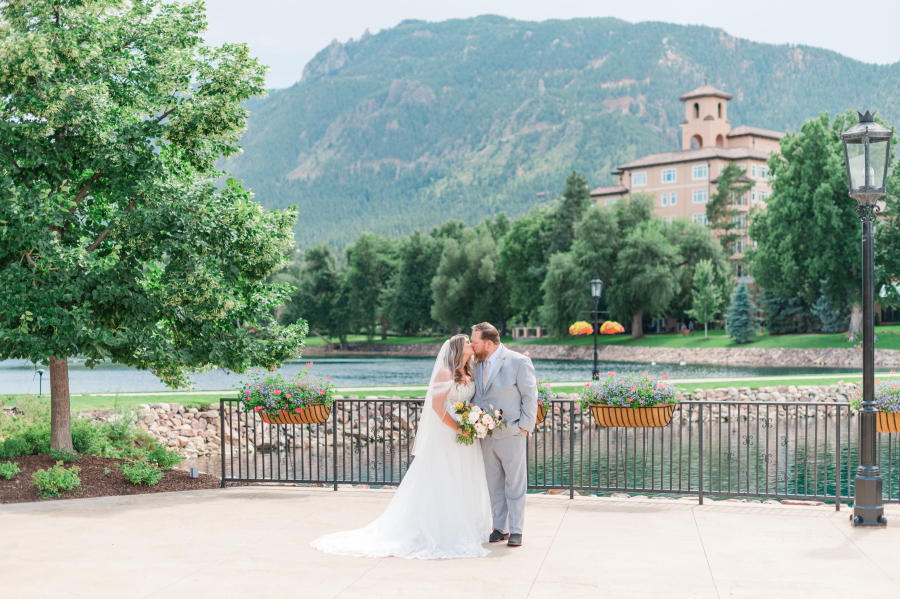 Newlyweds kiss by the water during their broadmoor hotel wedding