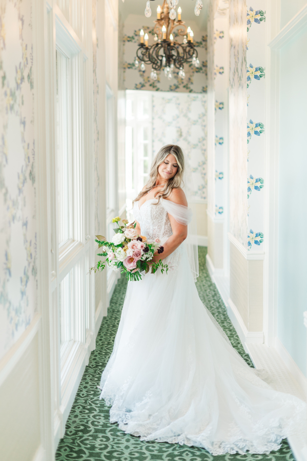 A bride smiles down her shoulder in a wallpapered hallway of the broadmoor hotel wedding venue