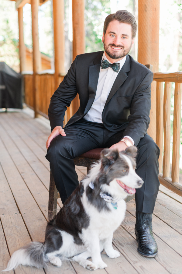A happy groom sits on a porch with his border collie before his camp hale weddings