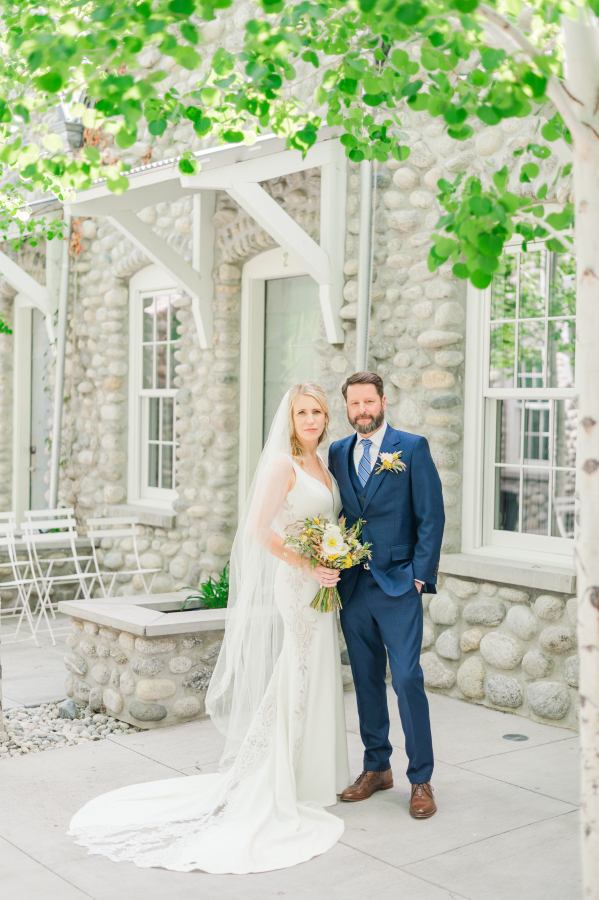 Newlyweds stand in the garden area lined in stone wall during their surf hotel wedding