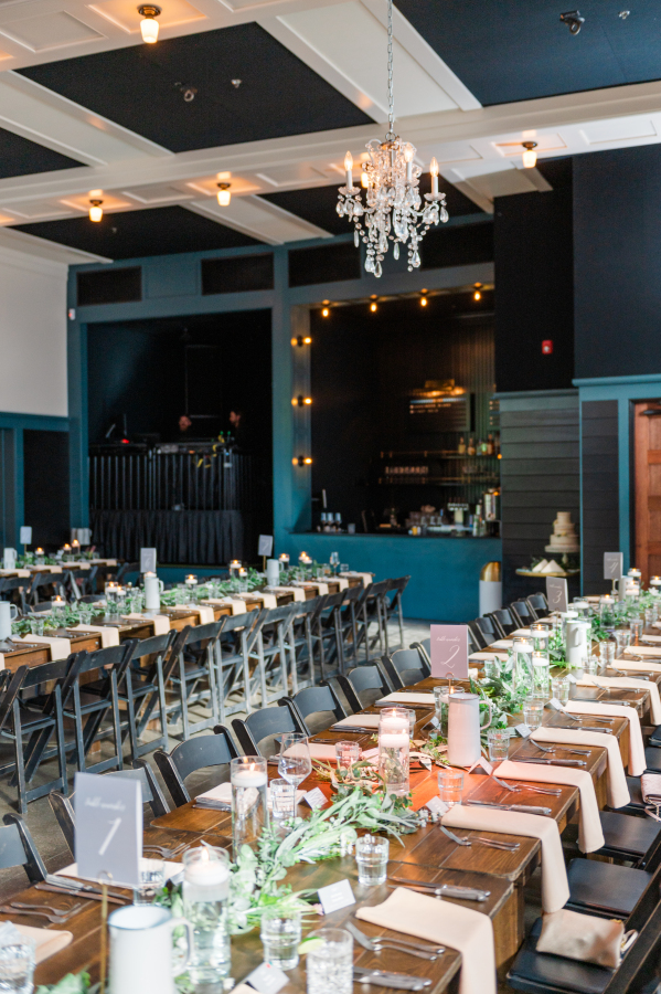 A look at a wedding reception set up with long tables and black chairs