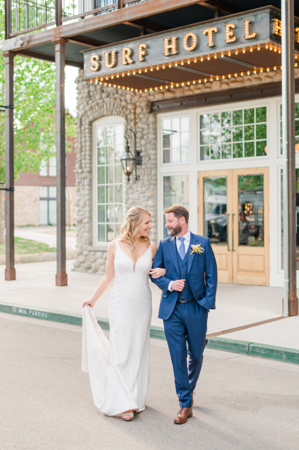 Newlyweds smile at each other while walking in the street outside the surf hotel wedding venue