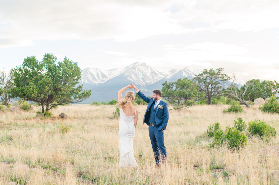 A groom twirls his bride while standing in a mountain meadow outside the surf hotel wedding venue