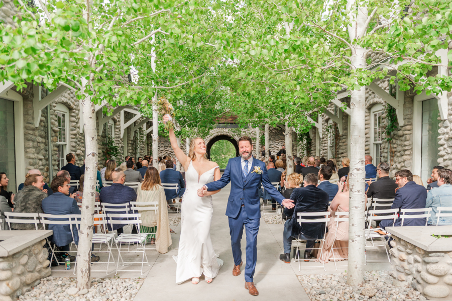 A bride and groom celebrate while exiting their outdoor surf hotel wedding ceremony with guests seated