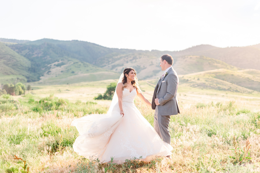 A bride dances and twirls with her groom in a mountain meadow at the the manor house wedding venue