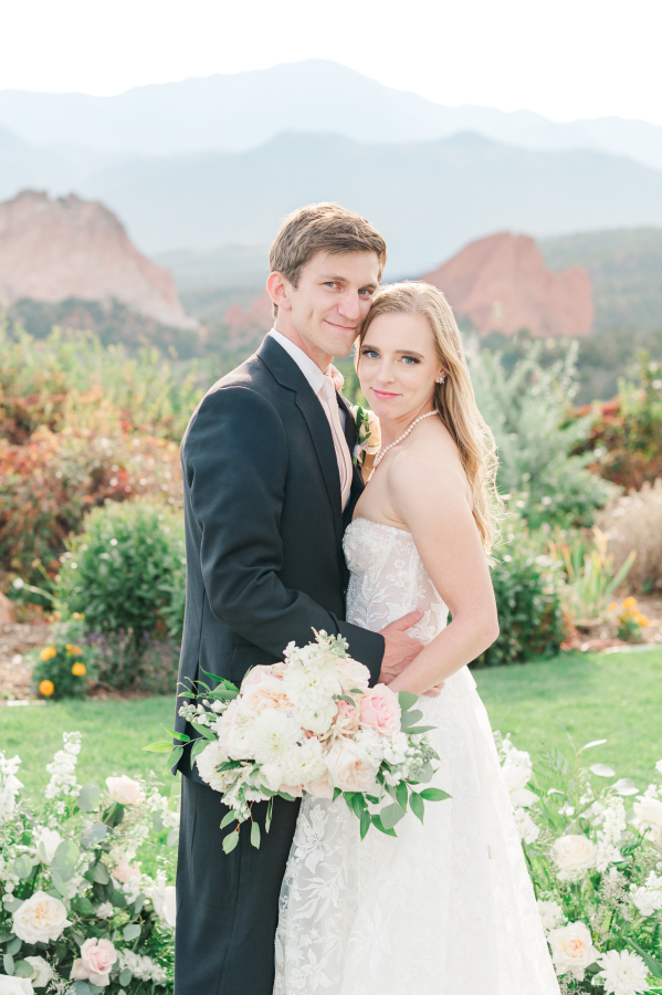 A bride and groom snuggle in a garden at one of the stunning Colorado Springs wedding venues
