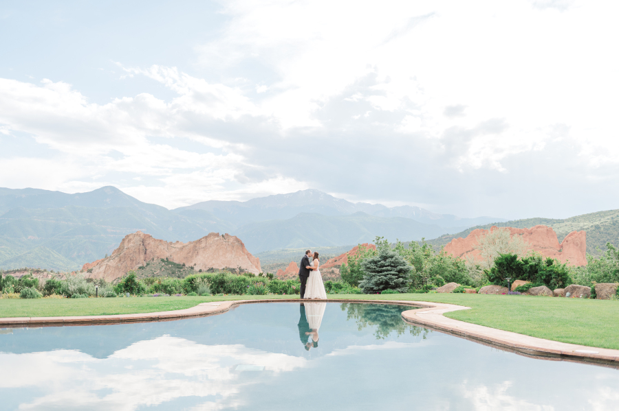 Newlyweds kiss in an epic wide shot of garden of the gods by the water