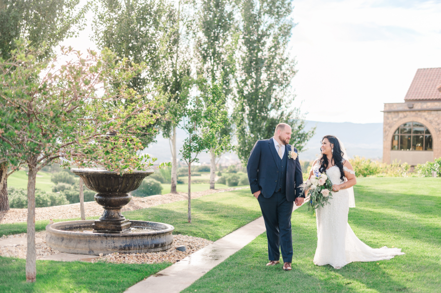 A bride and groom walk hand in hand through some gardens of the one of the Colorado Springs wedding venues
