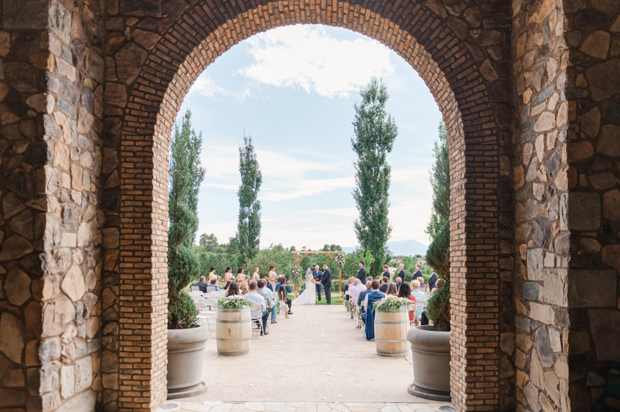 A look through a stone archway to a wedding ceremony in a patio