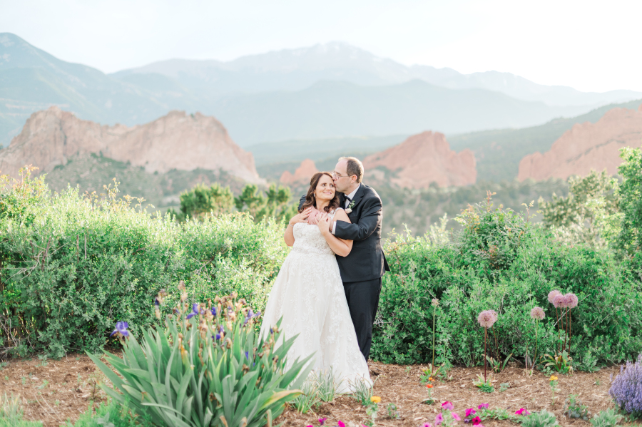 A bride and groom snuggle in the flowers at the garden of the gods resort wedding venue