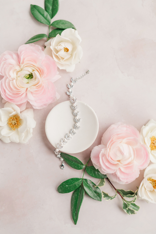 Bridal bracelet laying on a table with pink and white flowers