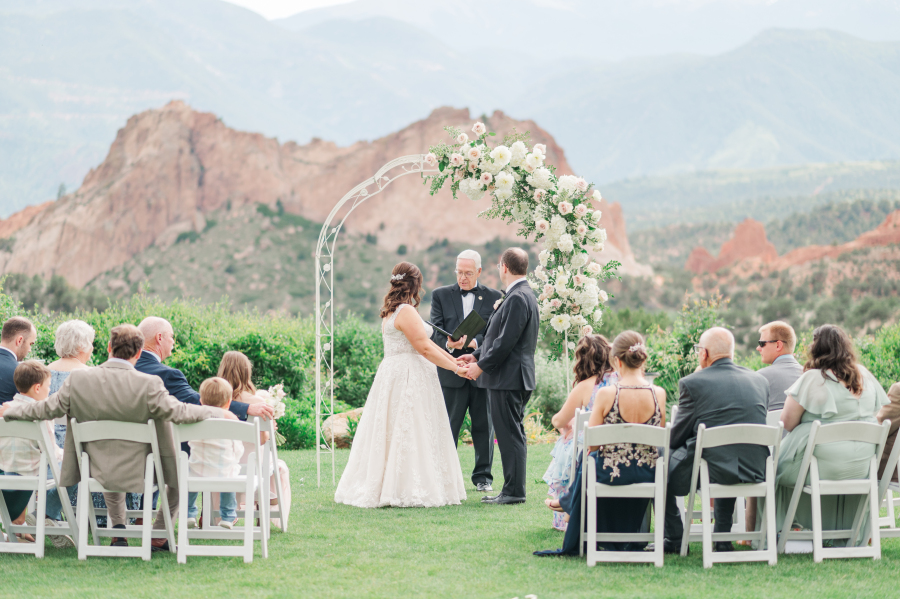 A bride and groom hold hands at the altar during a garden of the gods resort wedding ceremony under a wire arbor
