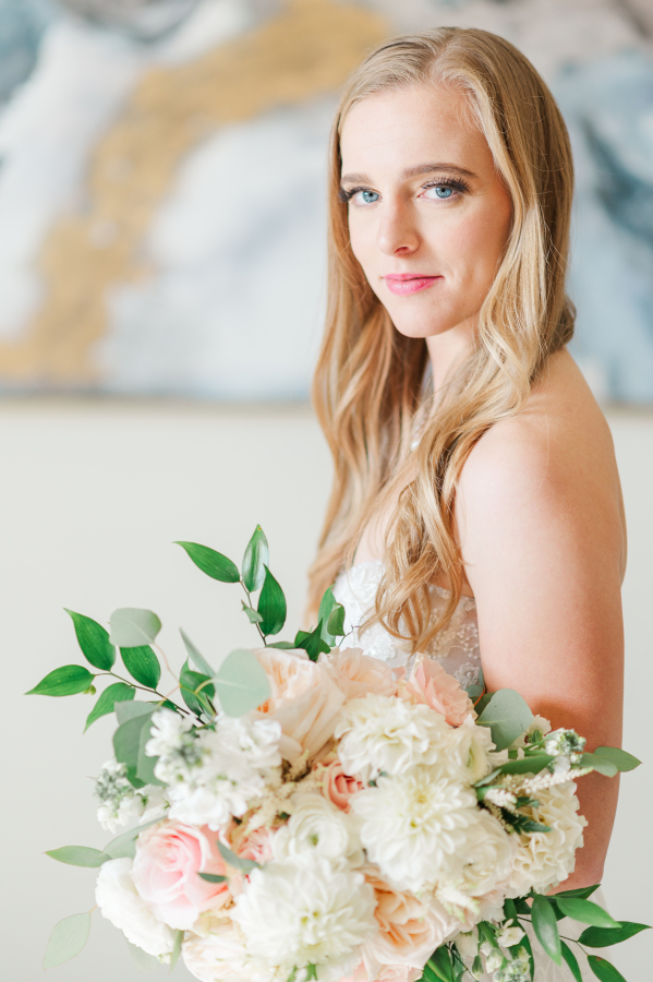 A bride looks over her shoulder while holding her white and pink bouquet at her garden of the gods resort wedding