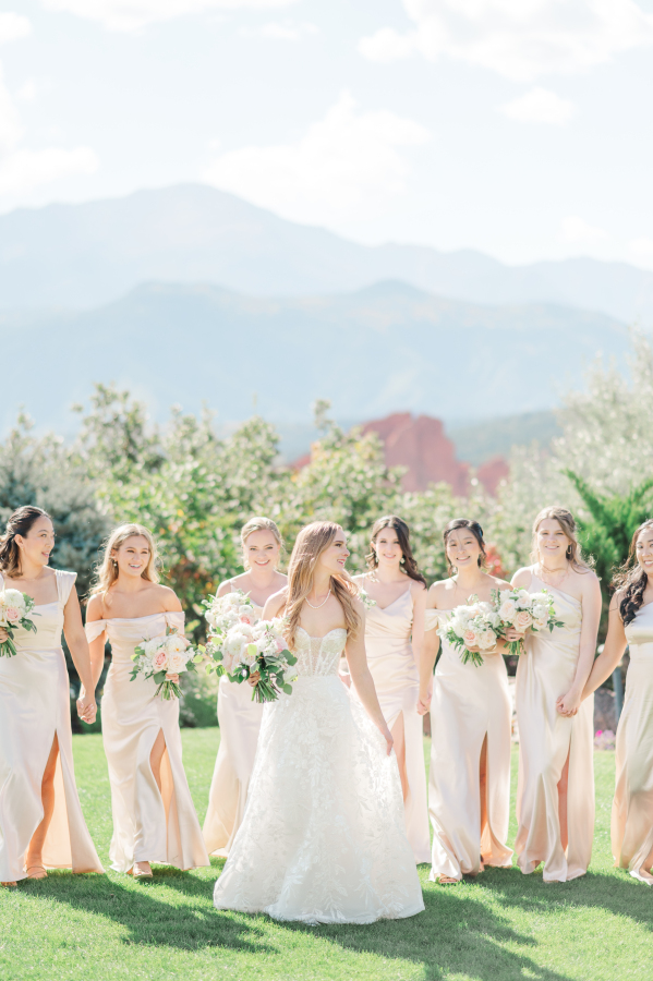 A bride walks with her bridesmaids in the lawn of garden of the gods resort wedding venue