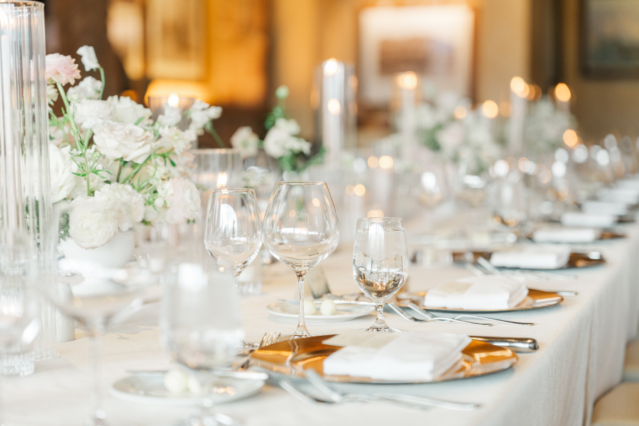 A look at a reception table setting on white linen with gold plates