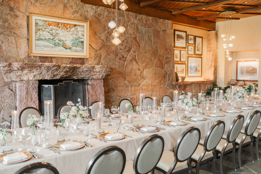 Details of a long white covered garden of the gods resort wedding reception table in front of stone fireplace