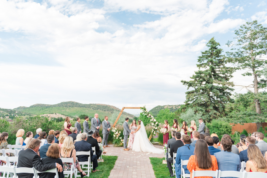 A peek at newlyweds at the altar holding hands during their outdoor ceremony at the manor house wedding venue