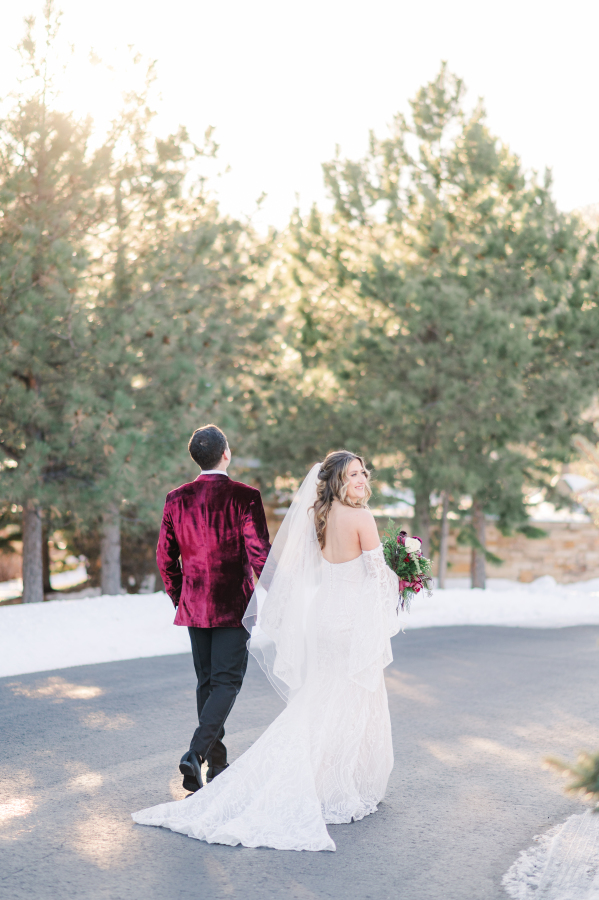 A happy bride and groom walk the sidewalk admiriing the spruce mountain ranch wedding venue at sunset