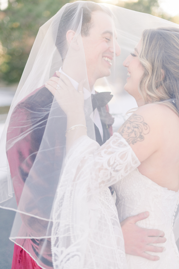 Newlyweds laugh while hugging under the veil at sunset during their spruce mountain ranch wedding