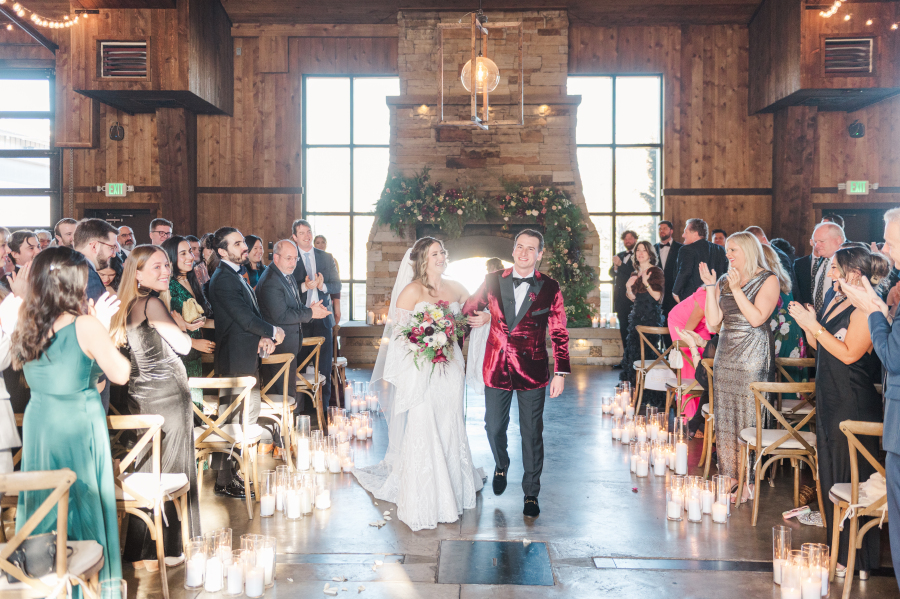 Newlyweds smile big while walking up the aisle to end their spruce mountain ranch wedding ceremony in front of fireplace