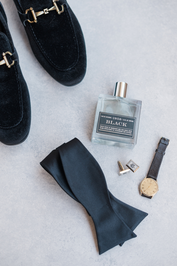 Groom details of shoes, cologne, bowtie and watch