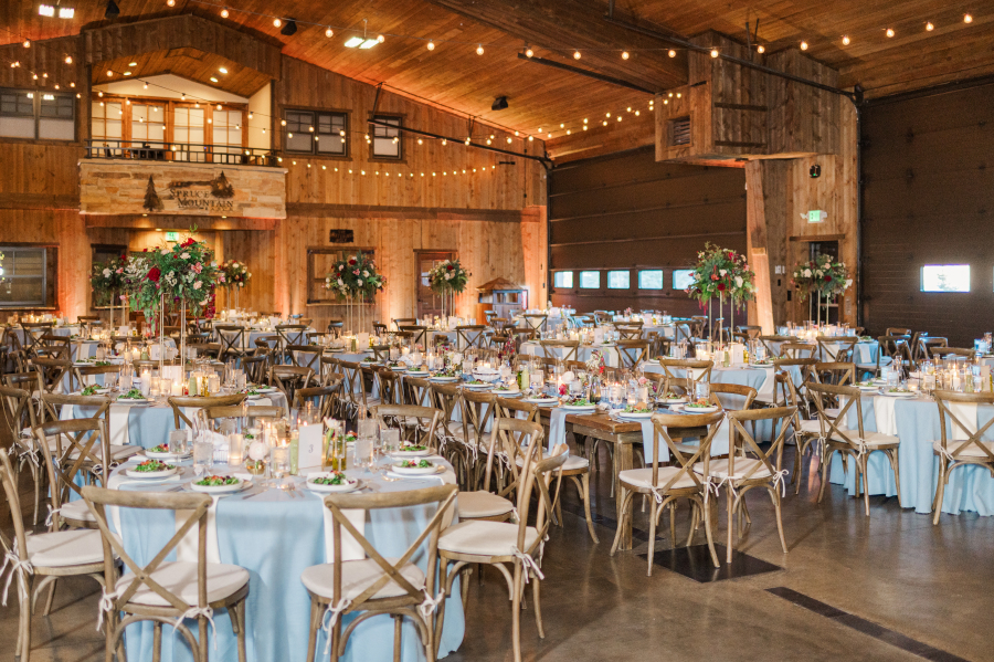 A look at a stunning spruce mountain ranch wedding reception set up with blue linens and wood chairs under string lights