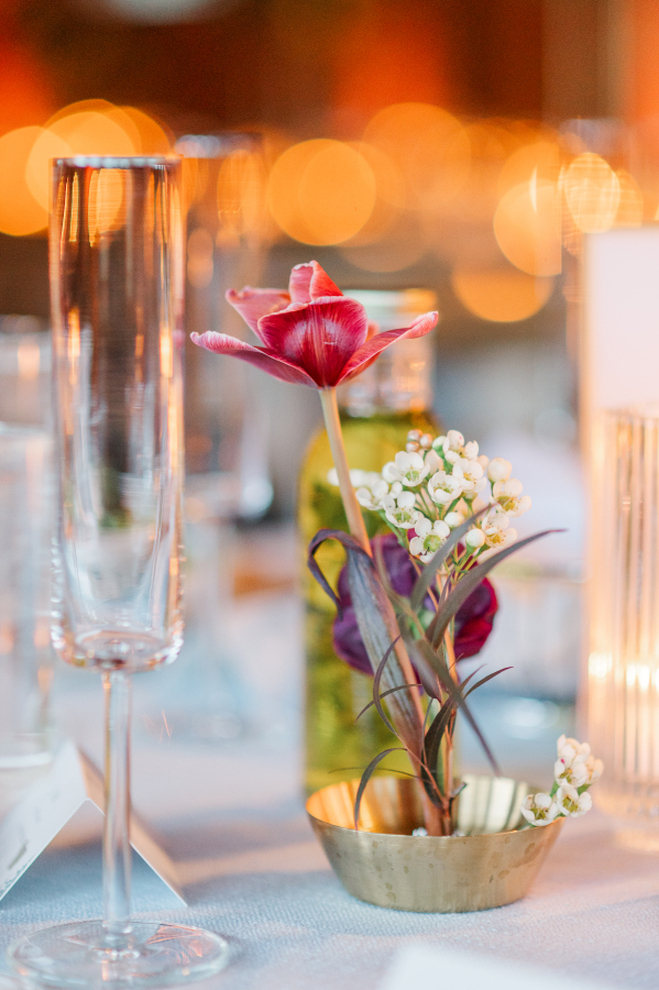 Details of a single pink flower in a copper cup on a reception table