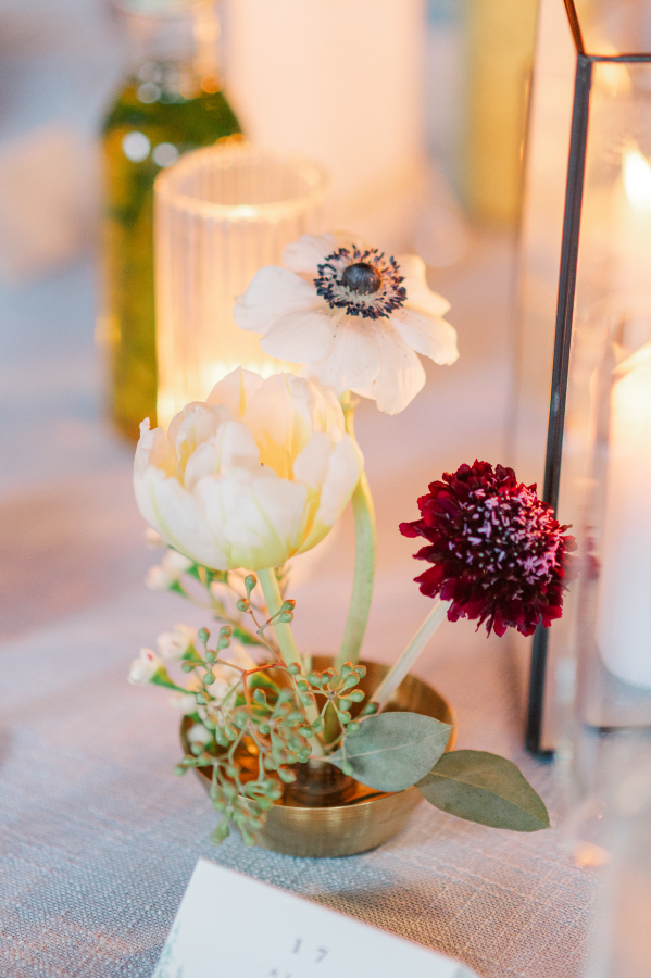 Details of a small white and red flower trio in copper on table